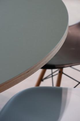„Detailaufnahme eines runden Tisches mit sichtbarer Holzschichtkante und reduzierter Innenraumgestaltung geplant und umgesetzt von arc+